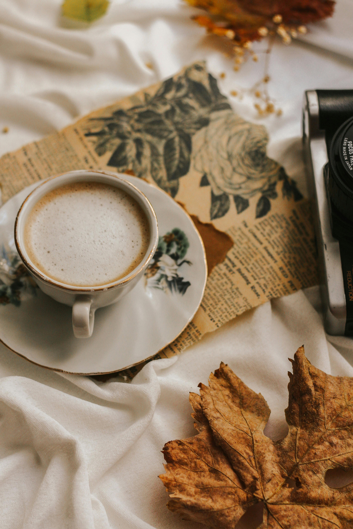 Coffee and autumn leafs on a white cloth