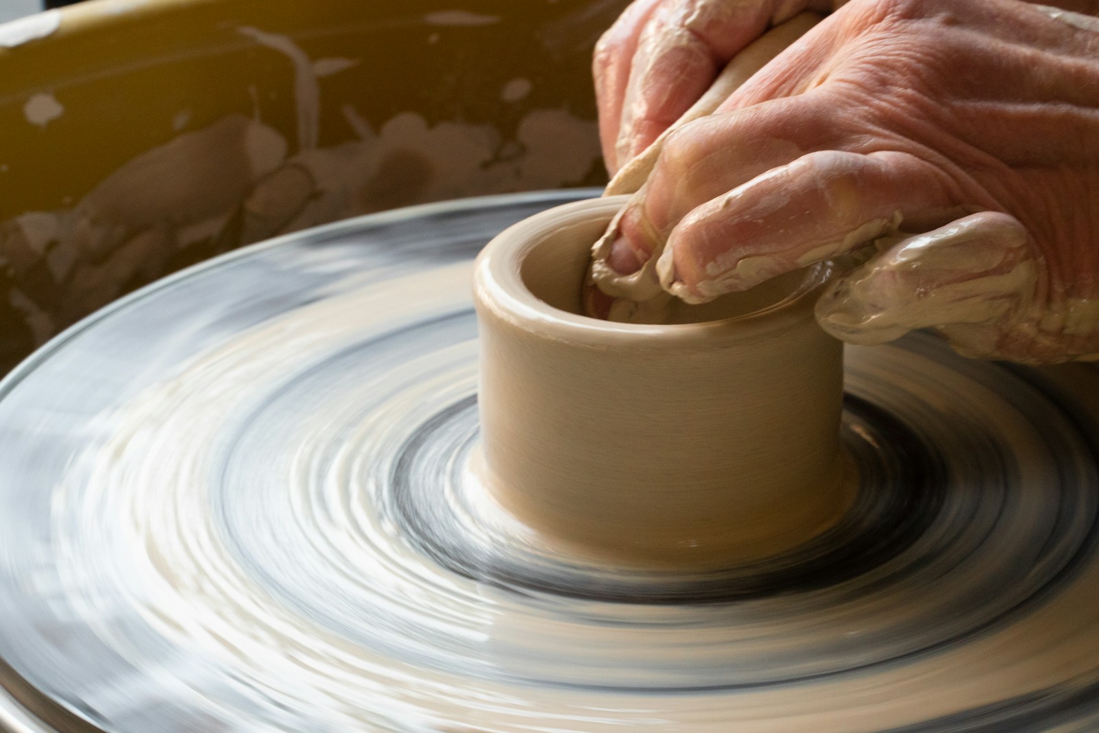 person making clay pot on white round plate
